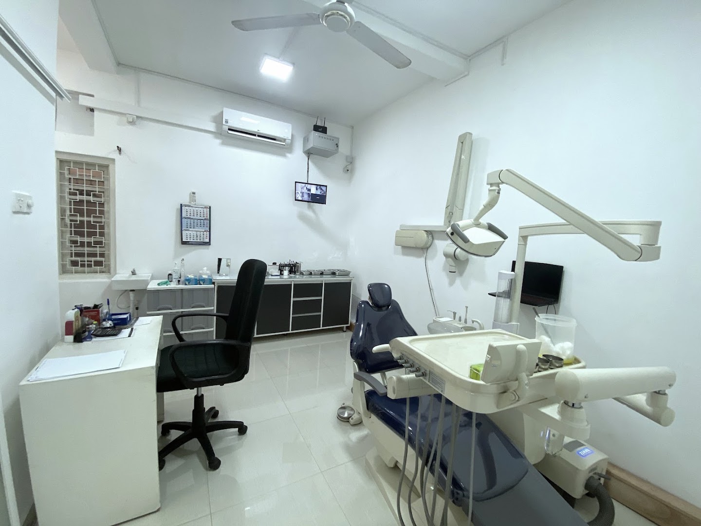 Dental treatment room with chair, equipment, desk, and storage